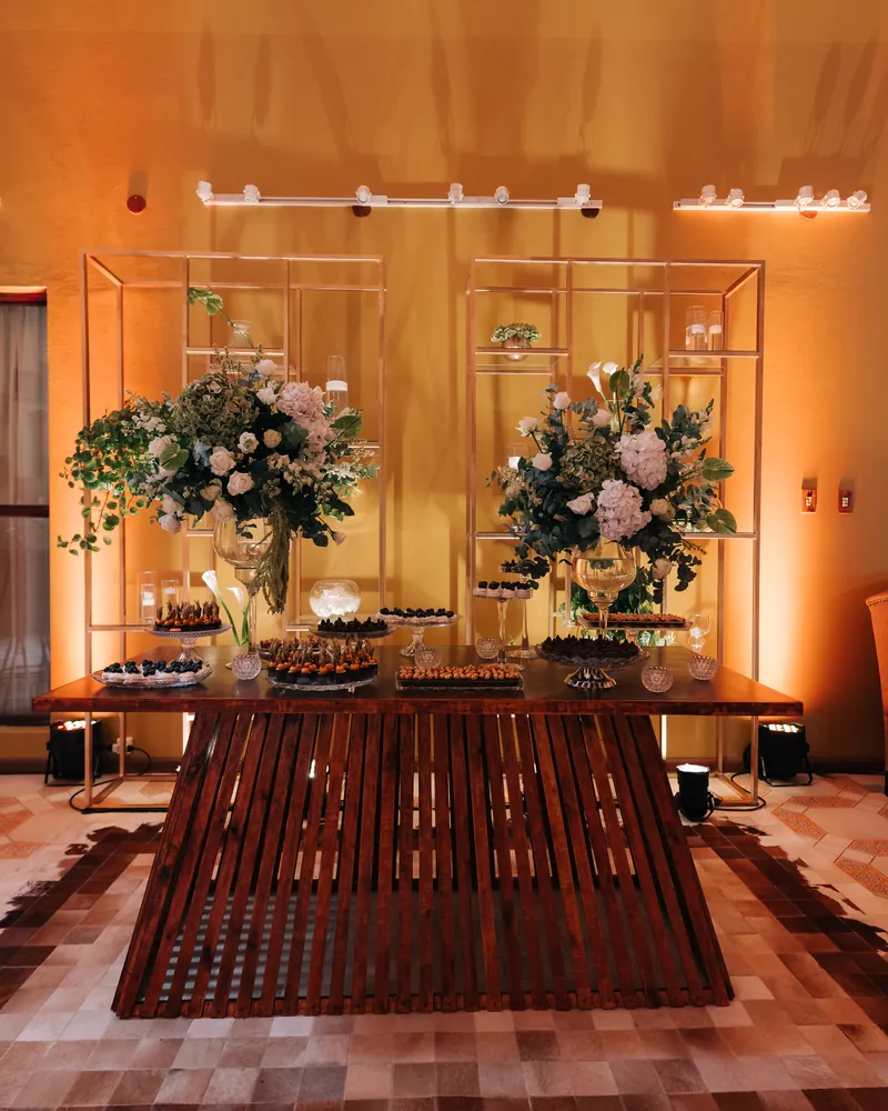 Mesa de doces com arranjos de flores brancas