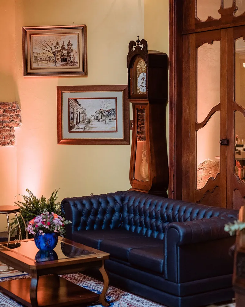 Sala com sofá de couro azul, quadros e relógio de pêndulo
