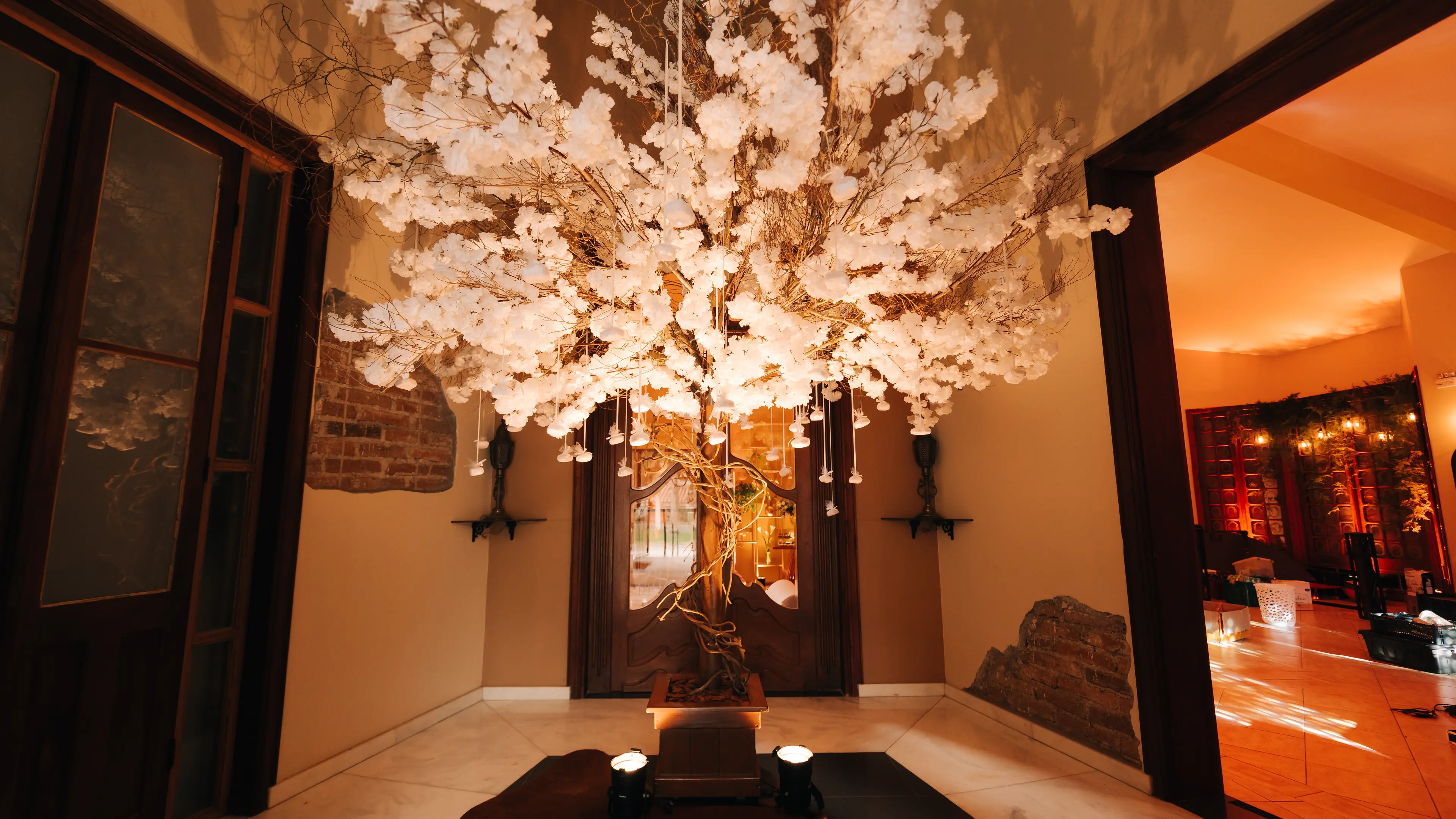 Árvore de flores brancas iluminada na entrada do salão